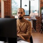 Business company entrepreneur thinking about financial solutions while sitting at desk in office