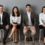 smiling interracial business people in formal wear looking at camera while waiting for job interview